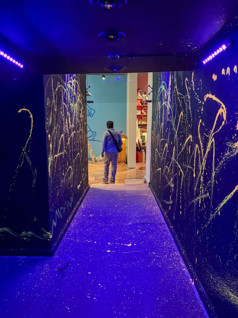 Pasillo oscuro iluminado con luz negra, decorado con pintura fluorescente en las paredes y el suelo durante una exposición en el museo Franz Mayer.